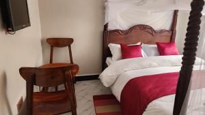 a bedroom with a bed with red and white pillows at Muzinge inn in Kagolomolo