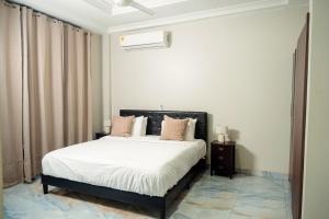 a bedroom with a bed with white sheets and pink pillows at Adonai Hotel & Apartment in Spintex