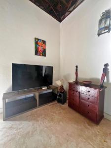 a living room with a large television and a wooden dresser at Mepoho Beach Villa Watamu in Watamu