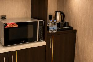 a microwave sitting on top of cabinets with bottles of water at Leaf Suites - أجنحة ليف in Ar Rass