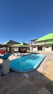 a large swimming pool with an umbrella and chairs at Pousada beira mar e sol in Tibau