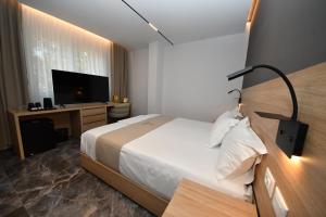 a bedroom with a bed and a desk with a television at Giulia Center Hotel in Tirana