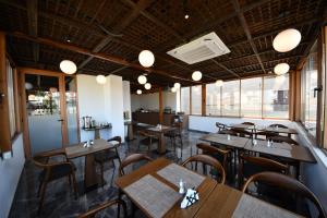 a restaurant with wooden tables and chairs and windows at Giulia Center Hotel in Tirana