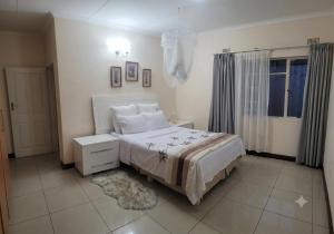a white bedroom with a bed and a window at Deluxe Studio Suite with Kitchenette in Gaborone