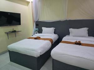 two beds in a room with a flat screen tv at The alder hotel and accommodation in Bungoma +13 photos