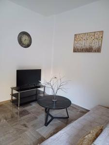a living room with a table and a tv at Cozy Corner Heraklion in Thérissos +3 photos