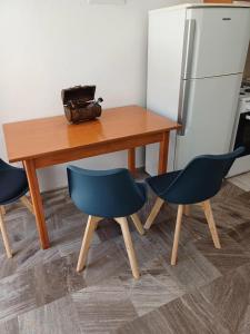 a wooden table with two chairs and a refrigerator at Cozy Corner Heraklion in Thérissos