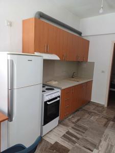 a kitchen with a white refrigerator and wooden cabinets at Cozy Corner Heraklion in Thérissos
