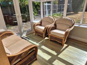 three wicker chairs sitting on a screened porch at Terling House in Hythe