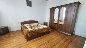 a bedroom with a bed and a large wooden cabinet at Gabe's house in Zugdidi