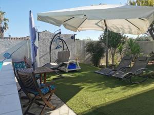 a patio with a lawn with chairs and an umbrella at Appartement dans villa avec jardin et piscine privée 4 personnes in Marguerittes