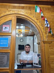a man sitting at a desk in an archway at Ho5tel House in Shymkent