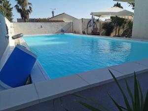 a large blue swimming pool next to a building at Appartement dans villa avec jardin et piscine privée 4 personnes in Marguerittes