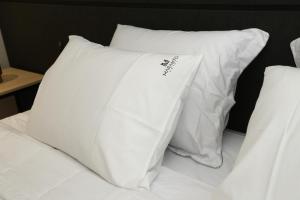 a pile of white pillows on a bed at Maranto Hotel in Pôrto União +46 photos