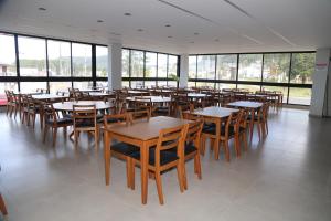 a dining room with tables and chairs and windows at Maranto Hotel in Pôrto União