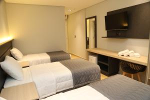 a hotel room with two beds and a desk at Maranto Hotel in Pôrto União