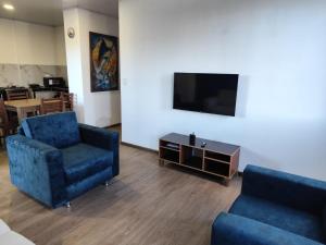 a living room with two blue chairs and a tv at Refugios del Pescador in San Cristóbal