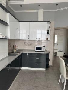 a kitchen with white cabinets and a sink and a microwave at Апартаменти біля чорноморського моря in Fontanka +3 photos