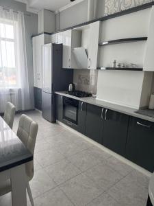 a kitchen with black and white appliances and a table at Апартаменти біля чорноморського моря in Fontanka