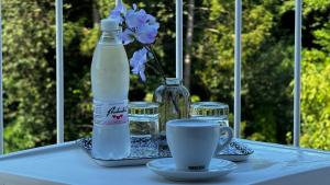 a table with a bottle of milk and a cup and flowers at Hotel Imperium in Moravske-Toplice