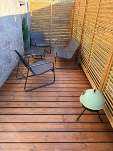 Drei Stühle und ein Tisch auf einer Holzterrasse in der Unterkunft Love room l'Evasion in Esprels