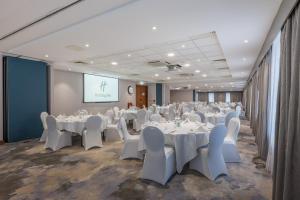 a conference room with white tables and chairs and a screen at Holiday Inn Stevenage by IHG in Stevenage