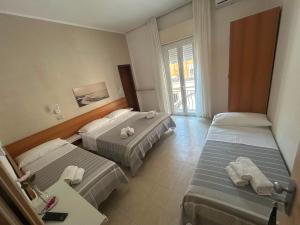a hotel room with two beds and a table at Hotel Fattori in Cesenatico +49 photos