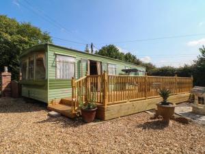 a green caravan with a deck and a fence at Buzzards Retreat in Wrexham