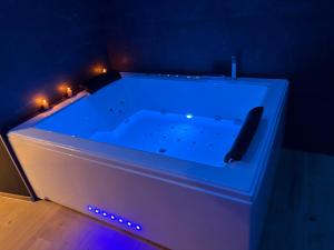 eine große blaue Badewanne mit Beleuchtung in einem Zimmer in der Unterkunft Love room l'Evasion in Esprels + 2 Fotos