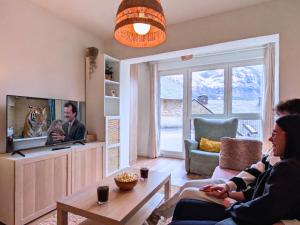 two people sitting in a living room watching a tv at Apartamento Casa Blanca in Tramacastilla de Tena