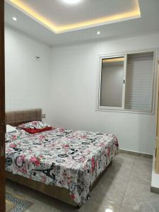 a bedroom with a bed with a floral comforter at Appartement lemjid in Kelibia +1 photo