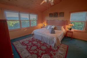 a bedroom with a bed with a rug and windows at Poppy’s Place Cabin in Dandridge +40 photos