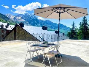 a table and chairs with an umbrella on a patio at Apartamento Casa Blanca in Tramacastilla de Tena