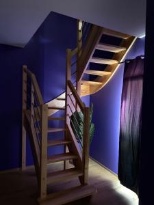 eine Holztreppe in einem Raum mit blauer Wand in der Unterkunft Love room l'Evasion in Esprels