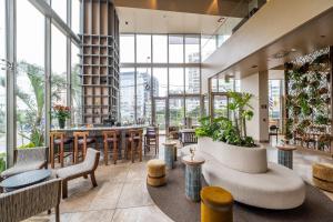 a lobby with tables and chairs and large windows at SOUMA Hotel, Vignette Collection by IHG in Lima