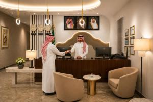 a man and a woman standing at a reception desk at Leaf Suites - أجنحة ليف in Ar Rass