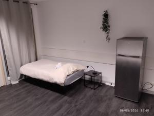 a small bedroom with a bed and a refrigerator at Le Lilas - 6 in Cherbourg en Cotentin