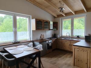 a kitchen with a table and some windows and a table at Domek na Polanie Rekowo in Pollnow
