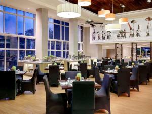 a dining room with tables and chairs and windows at Pullman Bali Legian Beach in Legian
