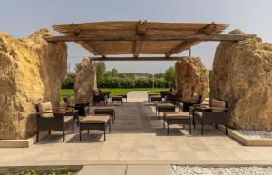 eine Terrasse mit Stühlen und Tischen zwischen zwei großen Felsen in der Unterkunft Corallo Home Resort in Le Castella