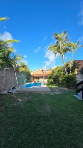 a yard with a swimming pool and palm trees at Acomodações as casinhas da ada in Coruripe