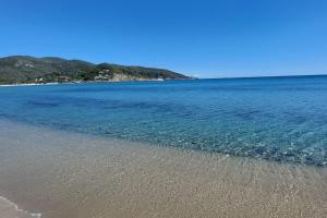 a beach with blue water and mountains in the background at Appartamenti L'Arcipelago in Marina di Campo