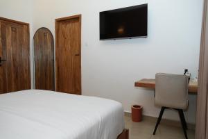 a bedroom with a bed and a desk and a television at Résidence L'Eau Vive in Cotonou