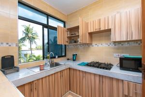 a kitchen with wooden cabinets and a large window at Dianiluxe Villa - Spacious studio 4 in Galu