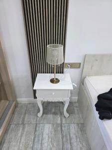 a white table with a lamp on it next to a bed at Smart Apartament in Brăila +2 photos