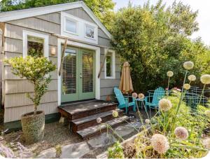 a tiny house with a wooden porch and blue chairs at Star Studio, A Garden Retreat near University of Oregon in Eugene