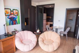 two pink chairs and a table in a room at EDGE Central Pattaya 2BR Ocean View Luxury Condo Rooftop Pool Central Location in Pattaya