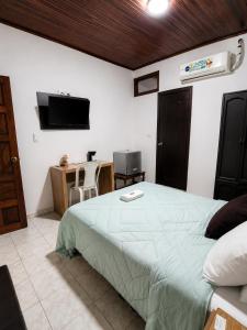 a bedroom with a bed and a desk and a television at Hotel Arauca Colonial in Arauca