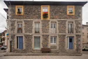 a stone building with blue doors and windows at Un buen día in Ramales de la Victoria