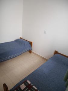 a bedroom with two beds and a blue rug at Ayinmai departamento C in Trelew